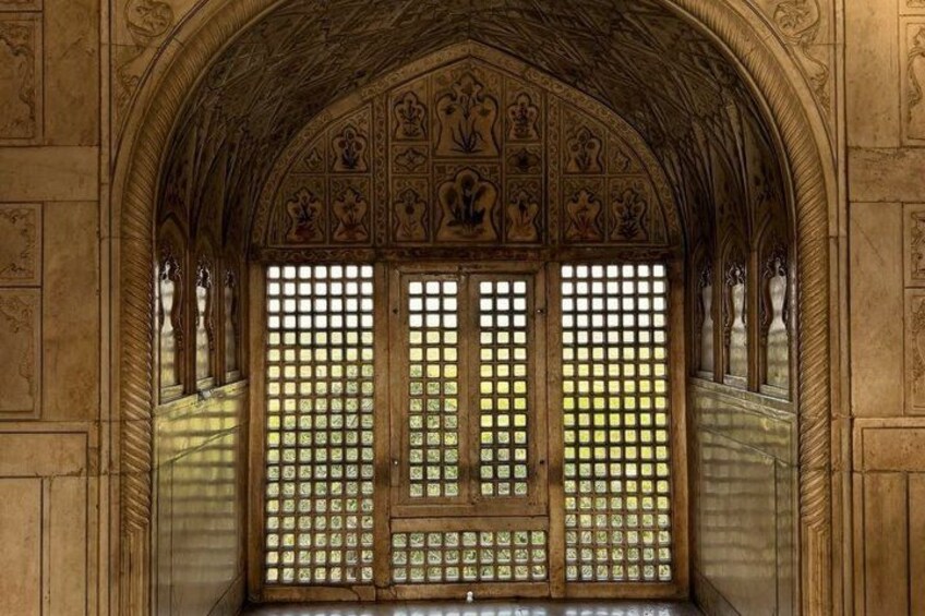 An arched doorway with intricate carvings and a lattice window. 3