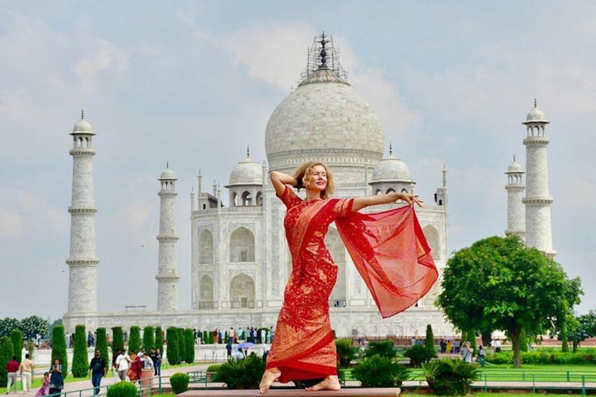 A person in a red dress posing in front of the Taj Mahal. 1