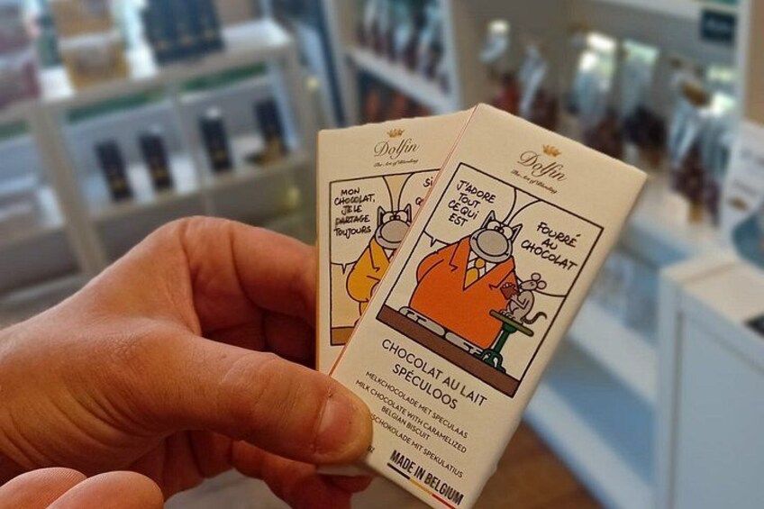 A hand holding two chocolate boxes with cartoon characters and text. 2