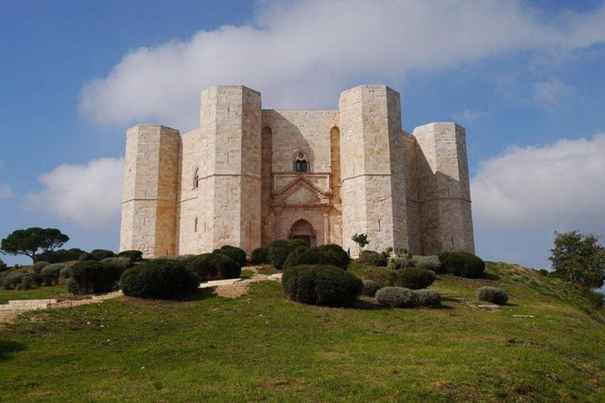 A historic stone castle with four towers, surrounded by a well-maintained grassy area and a few trees. 2