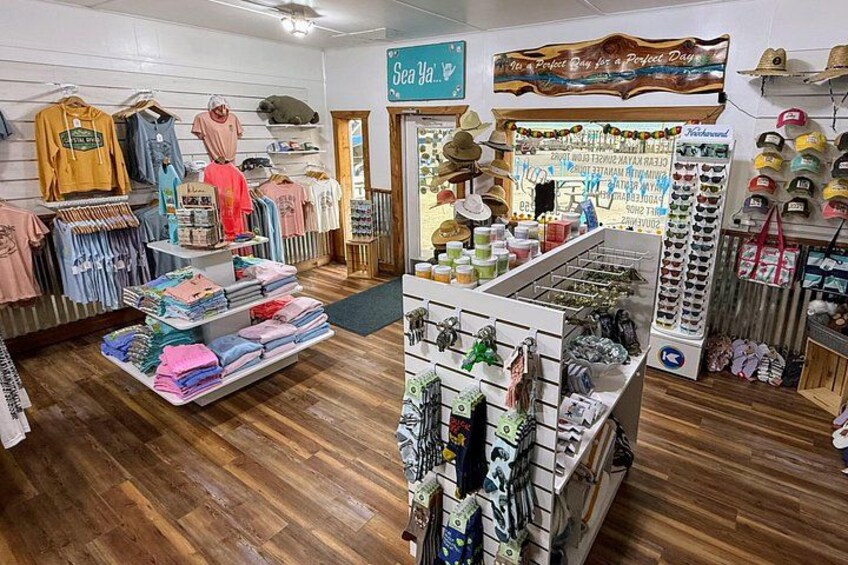 A clothing store with racks of clothes, a shoe display, and a sign that says 'Sea Bad.' 3