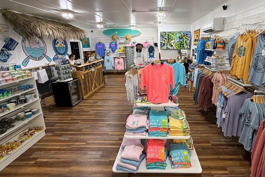 A clothing store with wooden floors, racks of clothes, and a display table with colorful items. 2