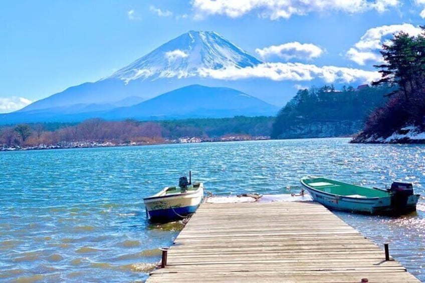 A wooden dock with two boats, a mountain in the background, and calm water. 1