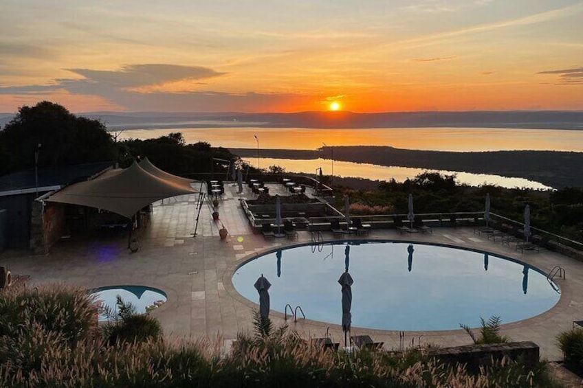 Un espace piscine avec vue sur le coucher de soleil, des sièges extérieurs et une tente. 1