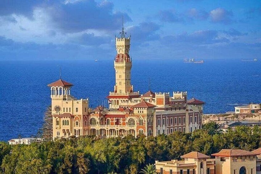 Un castillo costero con una torre destacada, rodeado de exuberante vegetación y el mar. 4