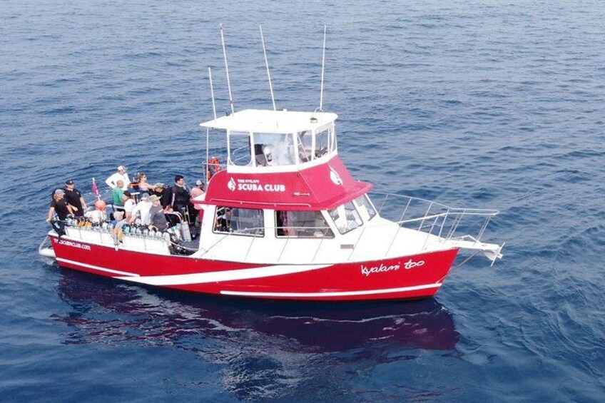 A red and white boat with 'SCUBA CLUB' written on the side, floating on water. 4