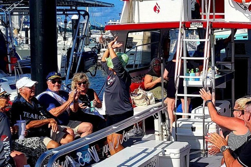 A boat with people on deck, a ladder, and a marina in the background. 5