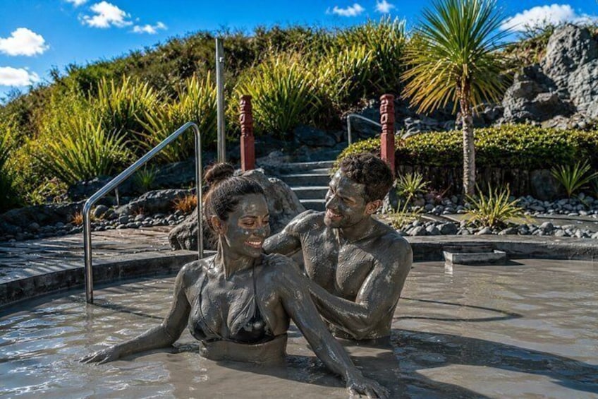 Una pareja en una piscina natural con paisaje rocoso y palmeras al fondo. 1