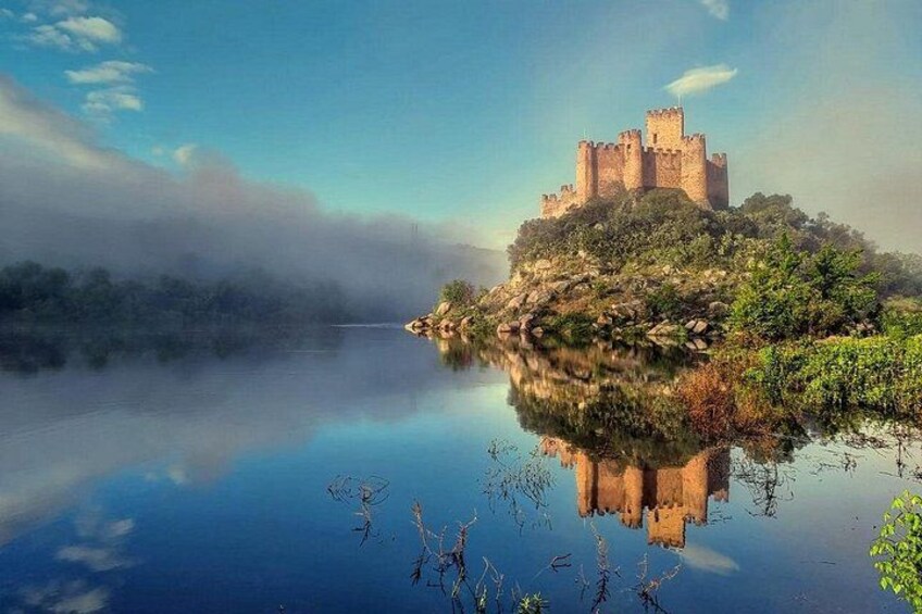 Un castillo en una colina con vistas a un lago tranquilo y neblinoso. 1