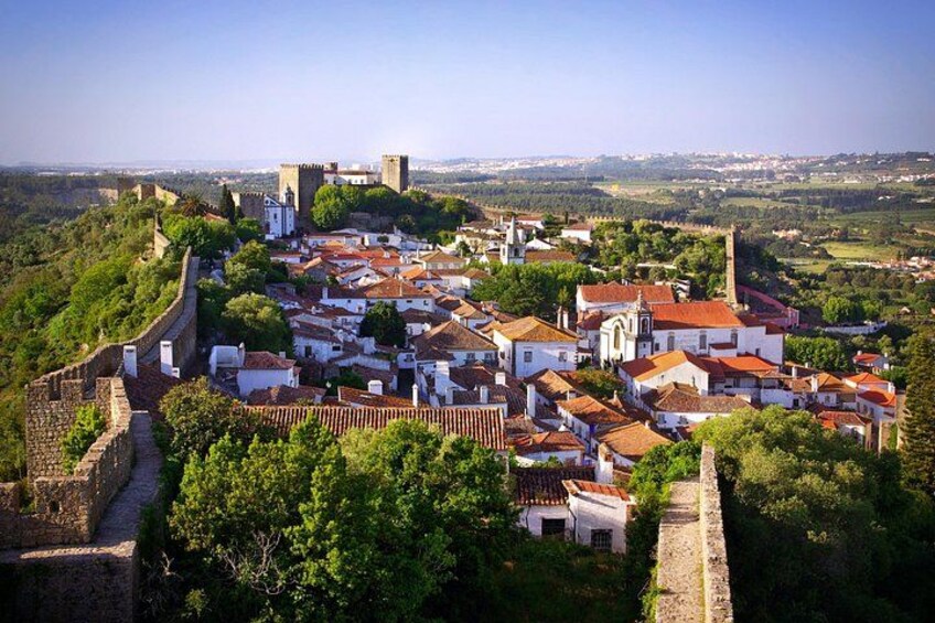 Un pueblo histórico con un muro fortificado, edificios con tejados rojos y una iglesia destacada. 5
