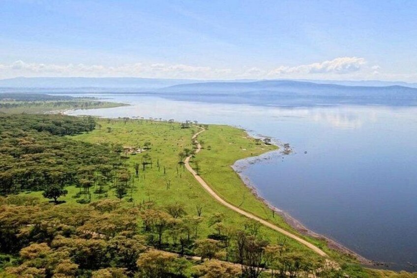A coastal landscape with a winding road, a calm lake, and distant mountains. 3
