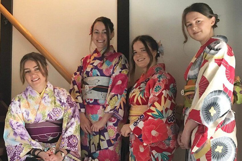 Fyra personer, klädda i färgstarka kimonos, står på en trappa. 3