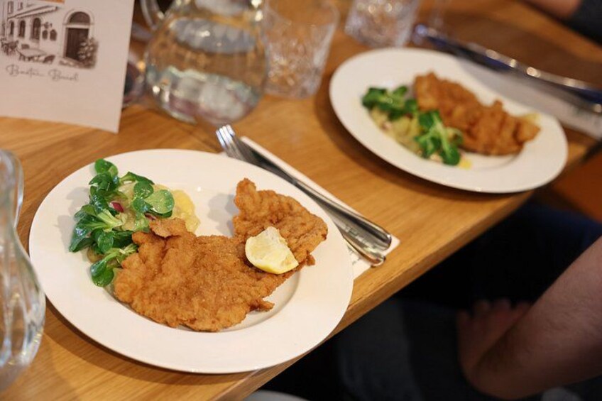 A plate of fried food with a lemon wedge and greens, and a menu card on the table. 5