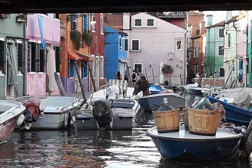 A narrow waterway with boats docked along the sides, surrounded by colorful buildings. 5