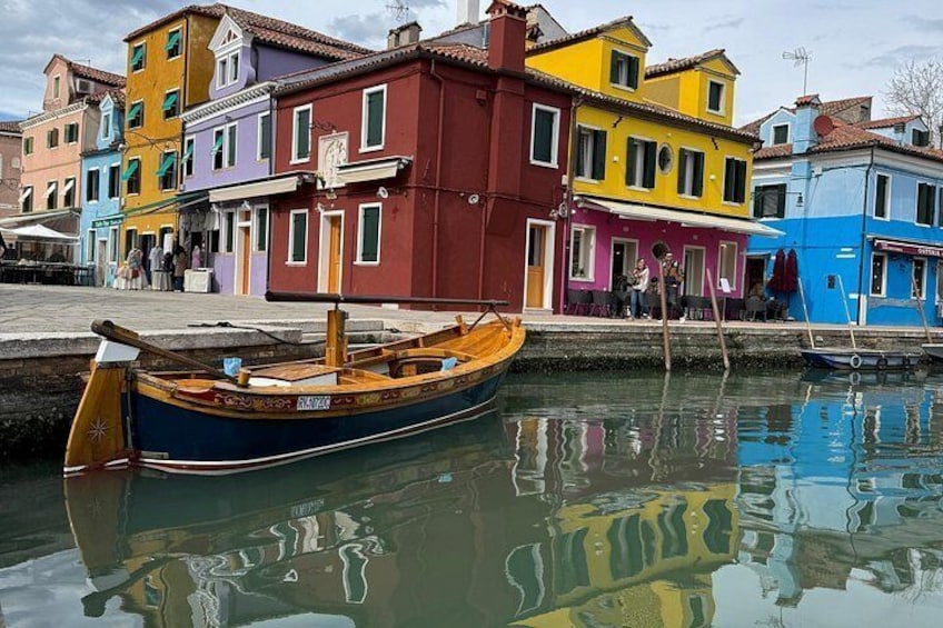 A colorful row of buildings along a canal with a wooden boat docked in the water. 1