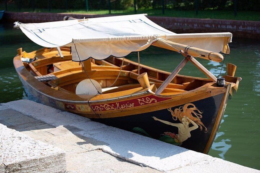 A wooden boat with a canvas cover docked at a concrete pier. 3