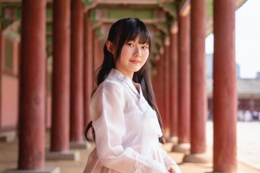 A person in traditional attire standing under a structure with red pillars. 4