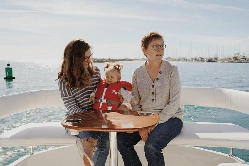 Deux adultes et un enfant sont à bord d’un bateau, avec une marina en arrière-plan. 3