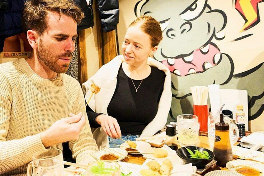 Two people dining at a table with various dishes and drinks. 1