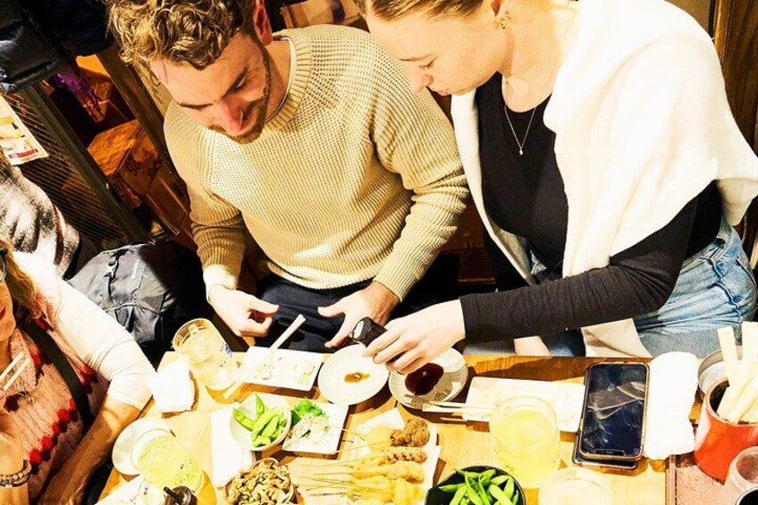 Due persone sedute a un tavolo con cibo, bevande, uno smartphone e un bicchiere. 5