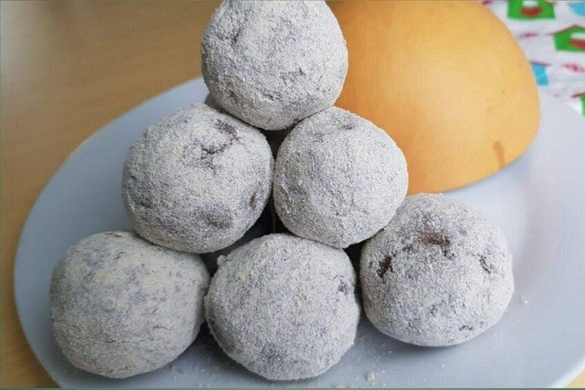 A plate of powdered sugar-covered cookies with a whole cookie beside them. 2