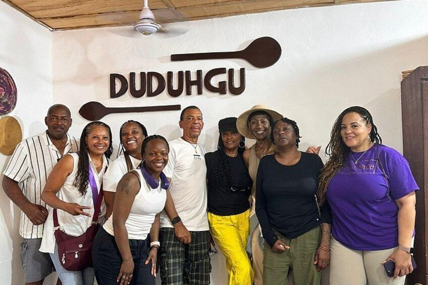 A group of people posing in front of a wall with the text 'DUDUHGU' and a paddle. 1