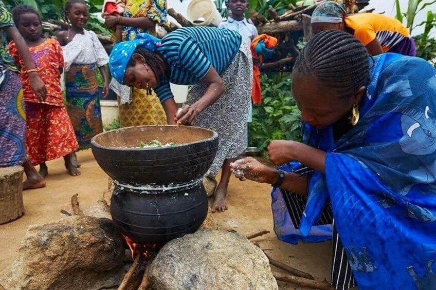 People cooking outdoors with a large pot over an open fire. 3