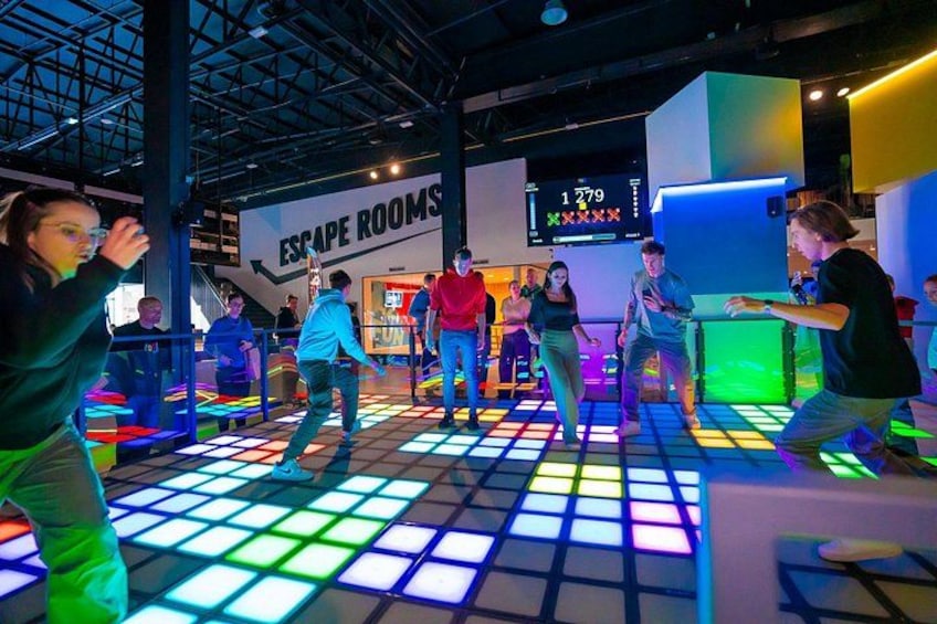 People dancing on a colorful illuminated floor in an indoor setting. 2