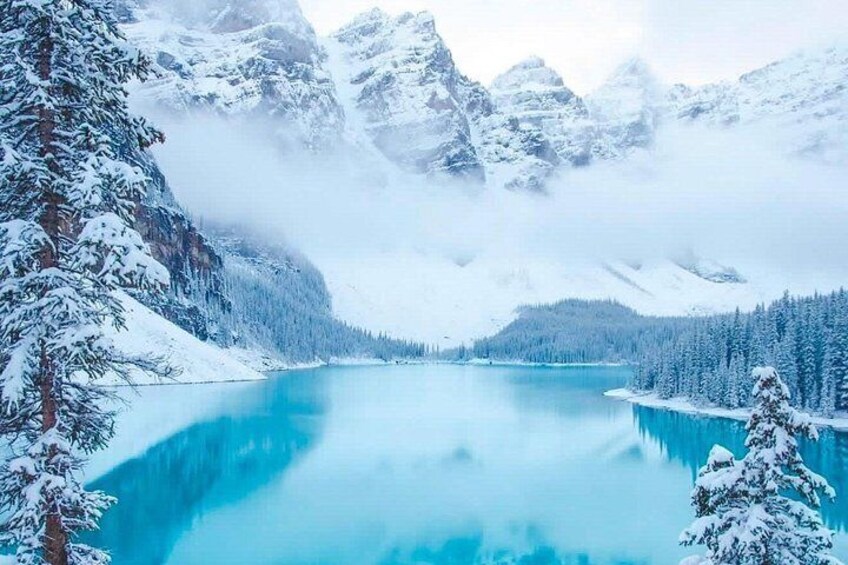 A snow-covered lake surrounded by mountains and trees. 5