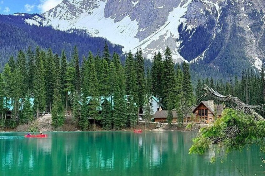 A lake surrounded by evergreen trees, a cabin, and a mountain backdrop. 3