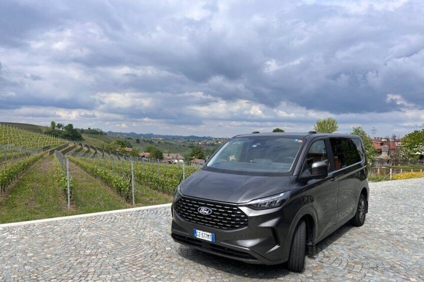 Un SUV de couleur sombre était garé sur un chemin pavé, avec des vignobles en arrière-plan. 3