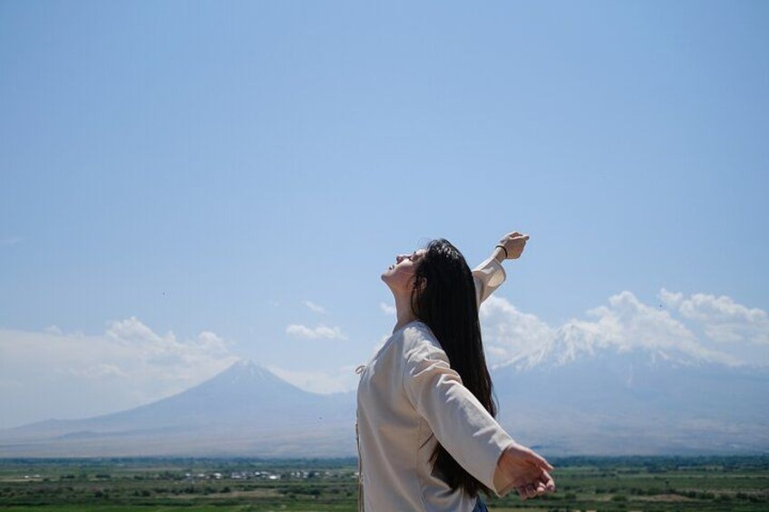 A person with arms raised, a mountain in the background, and a clear sky. 5