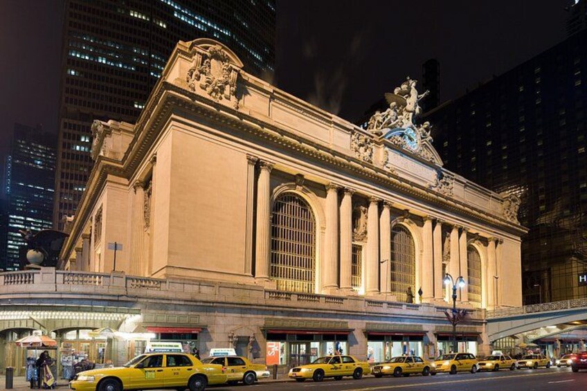 A grand building with classical architecture, a busy street with yellow taxis, and modern skyscrapers in the background. 3