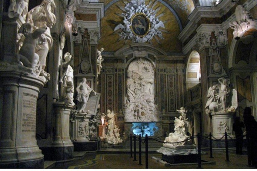 An ornate interior with classical sculptures and detailed wall decorations. 2