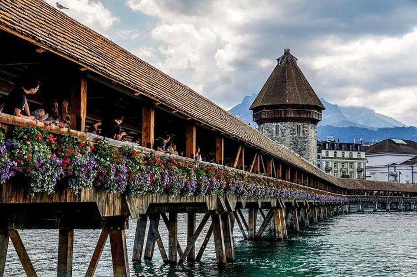 Un ponte di legno con composizioni floreali, una torre e una montagna sullo sfondo. 2