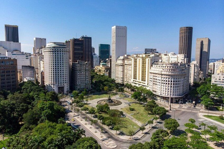 A cityscape with modern high-rise buildings, a central roundabout, and surrounding greenery. 2