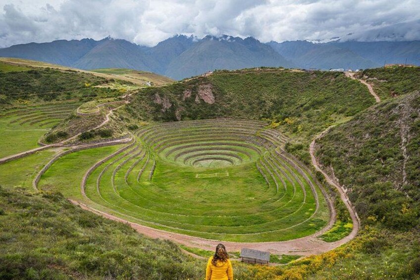 A terraced agricultural field with a winding path, surrounded by mountains and a cloudy sky. 1