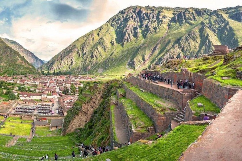 A mountainous landscape with terraced fields, a village, and a stone structure with people gathered around. 3