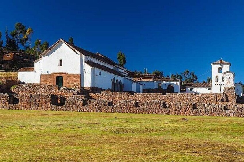 A white church with a bell tower, surrounded by stone walls and a grassy field. 5