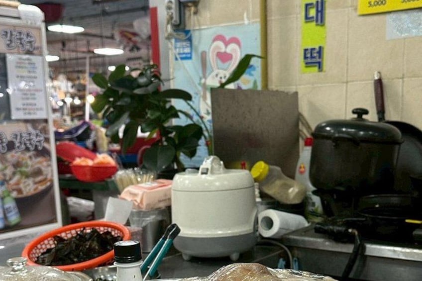A kitchen counter with a rice cooker, a plant, and various kitchen items. 2