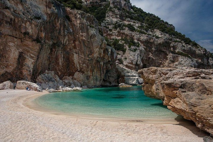 A beach with clear turquoise water, white sand, and rocky cliffs. 5