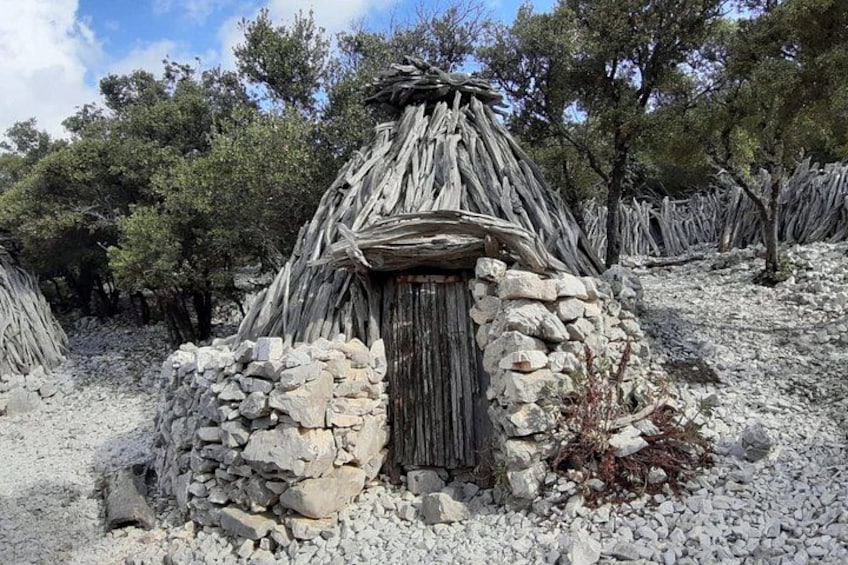 A traditional stone hut with a wooden door, surrounded by a rocky landscape and sparse vegetation. 2
