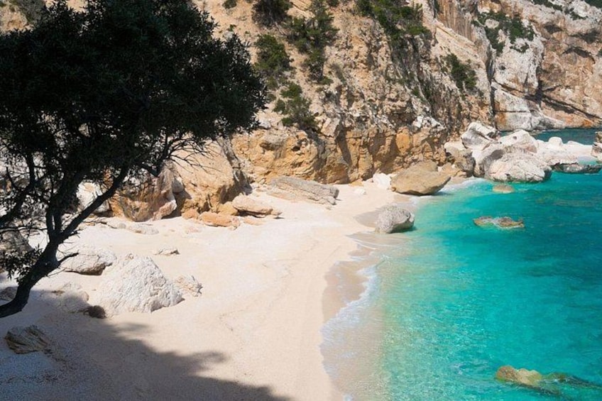 A beach with clear turquoise water, white sand, and rocky cliffs. 3