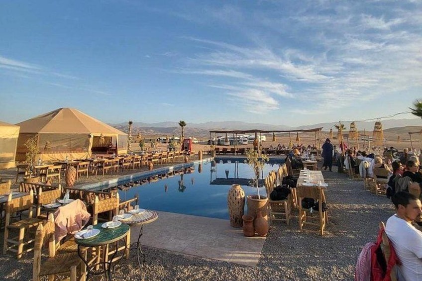 A desert resort with outdoor dining tables, a swimming pool, and tents. 1