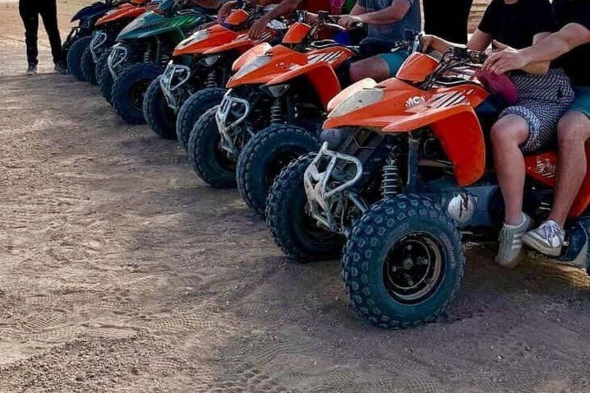 A row of quad bikes parked on a dirt surface. 4