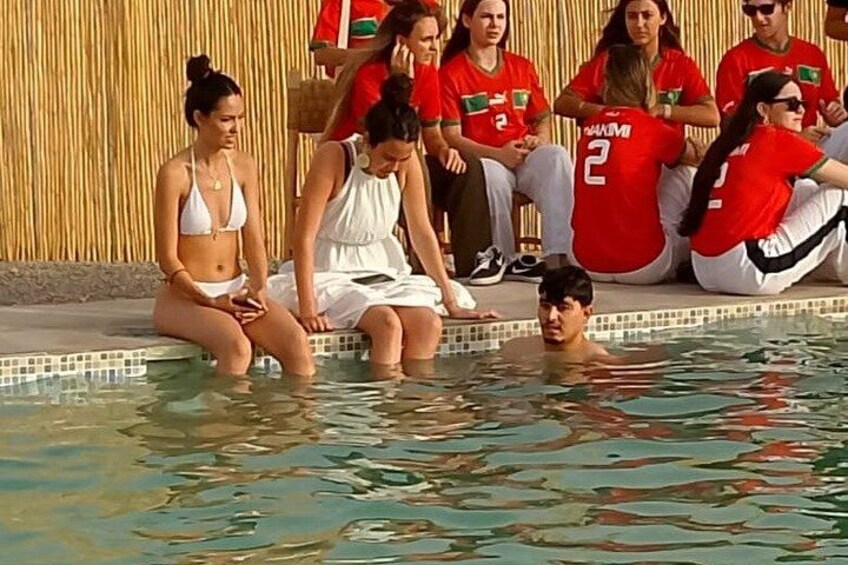 People sitting by a pool, some in red shirts, others in white. 3