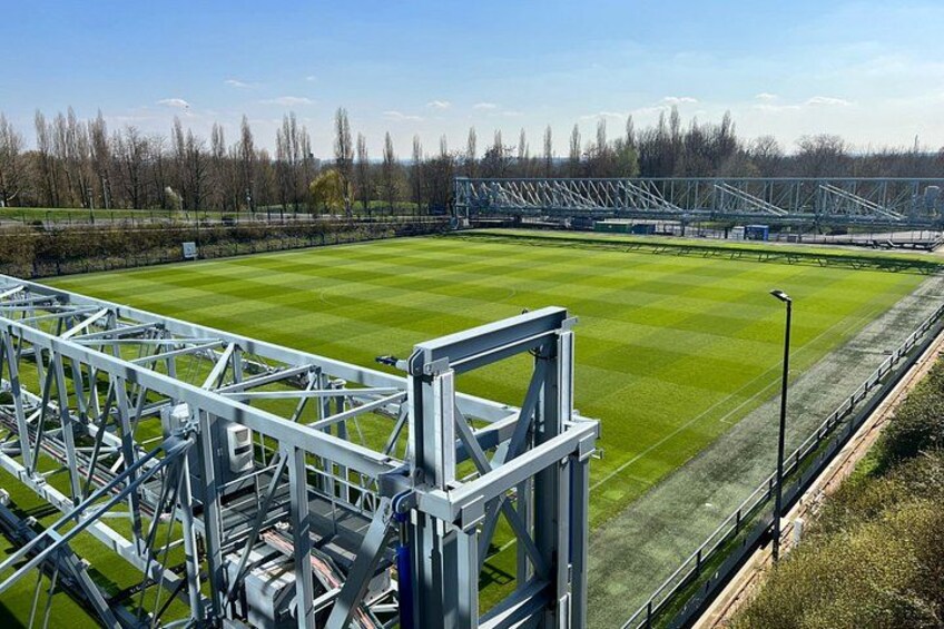 A sports stadium with green grass, metal bleachers, and a clear sky. 3