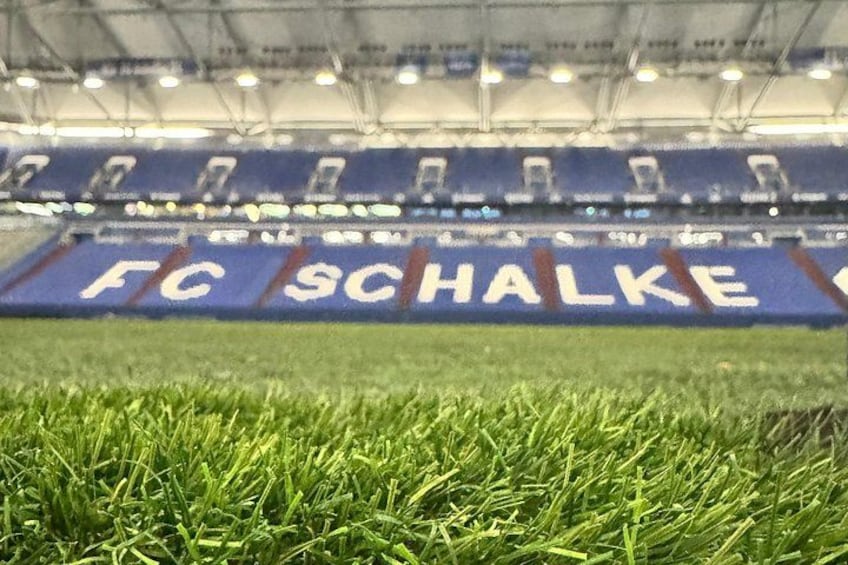 A stadium with a blue seating area and the text 'FC SCHALKE' on the seats. 2