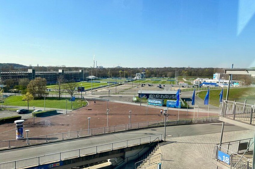 A parking lot with a bus, a bridge, and a building in the background. 4