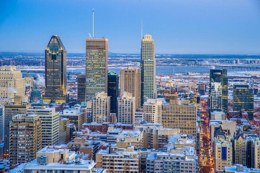 A cityscape with tall buildings, snow on the ground, and a clear sky. 4